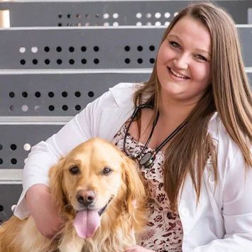 smiling female veterinarian holding her golden retriever