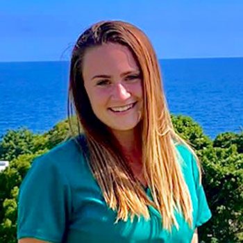 smiling female veterinarian standing in front of large body of water