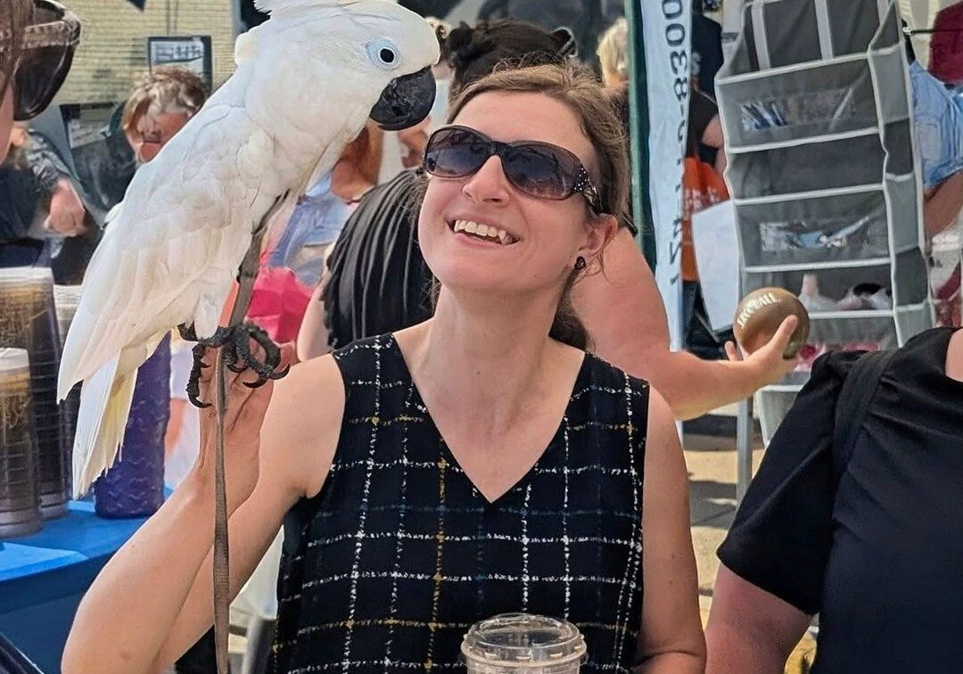 woman holding an exotic bird and an iced coffee